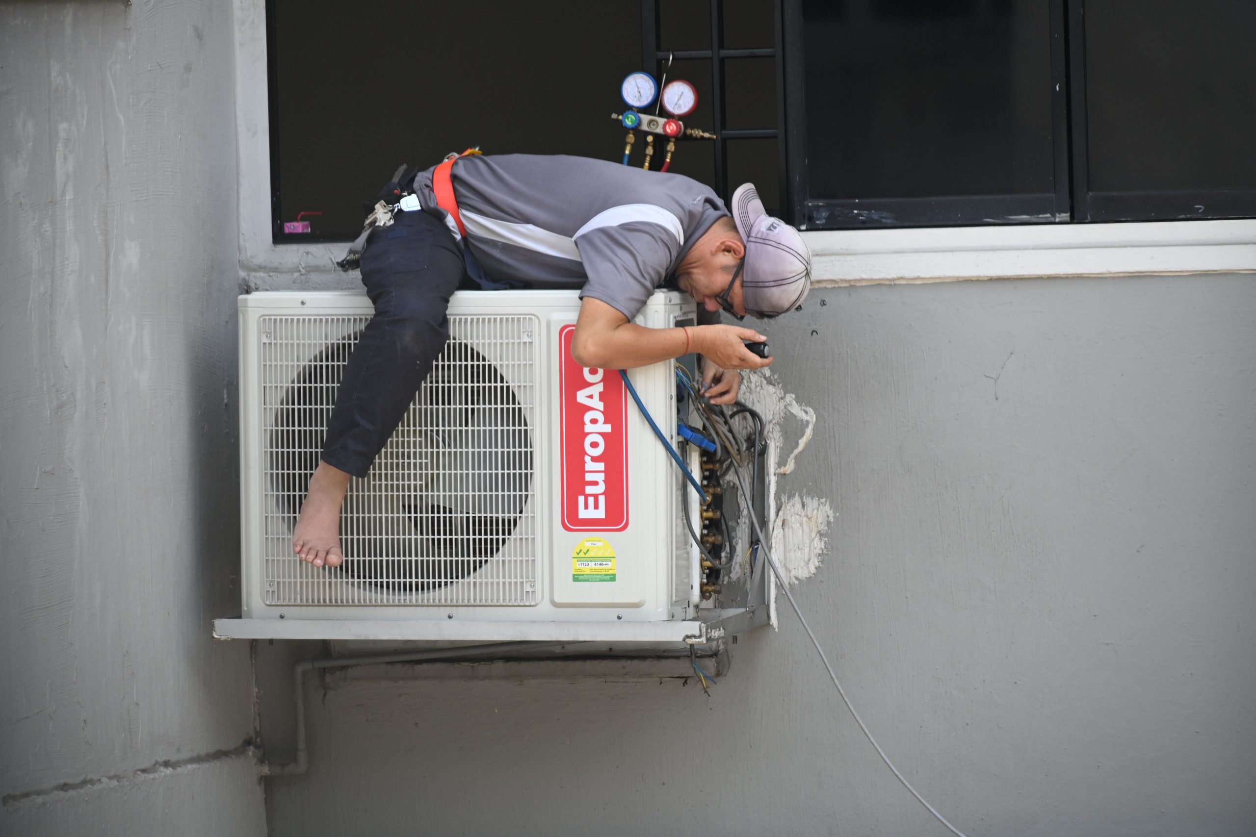 Technician Repairing HVAC System on Building Exterior Wall